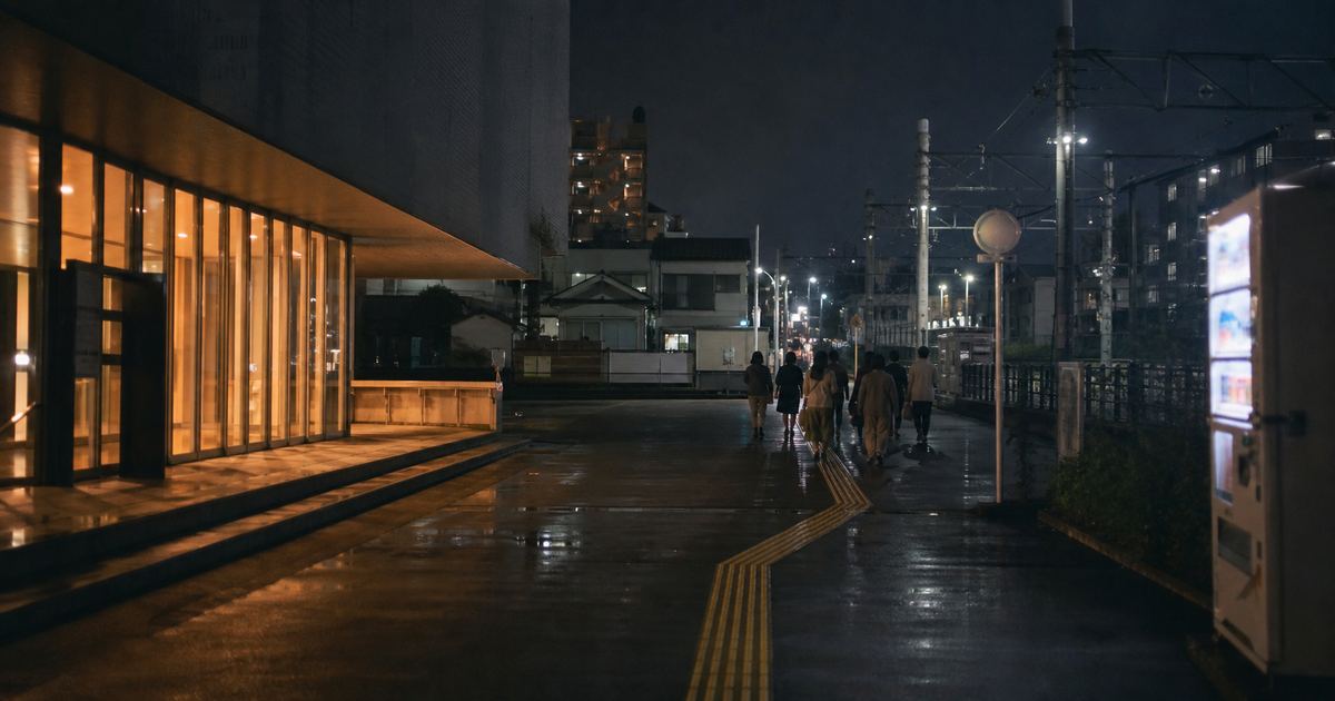 夜、ホールの明かりが漏れる通りを、観客がバス停へ向かって歩いている(イメージ)