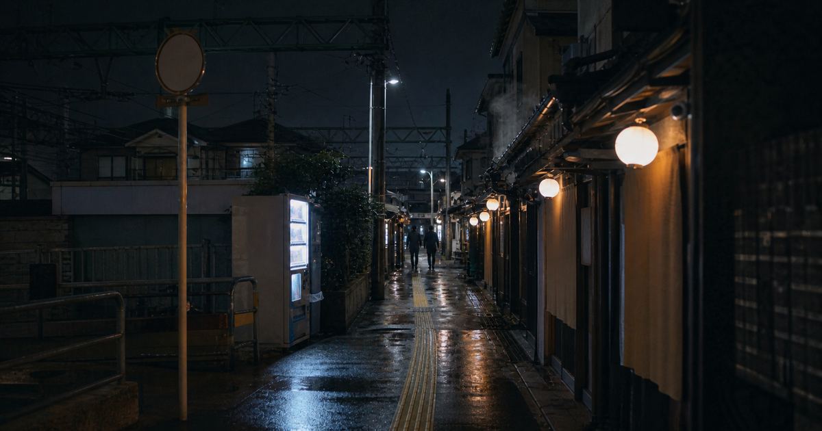 夜の飲食店街。提灯の灯りと自販機の光が路地を照らしている（イメージ）